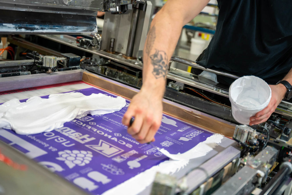 Drucktechniker der weisse Farbe durch ein Sieb presst